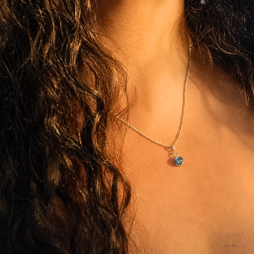 HEAVEN halsband med kyanit cabochon 8mm i stainless steel bezel-infattning, aftonstämning, bärt mot varm hud med vågigt hår, av smyckesbutiken HerMine's. Premiumkänslan.