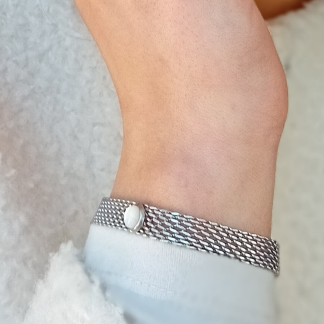 Close-up of LUNË bracelet highlighting stainless steel mesh texture and mother of pearl detail with subtle iridescent glow.