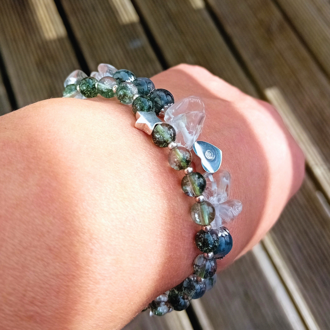 MIRA staplad med FAELYN på handleden, gröna fantomkvartspärlor och en stjärna i silver bredvid ett armband med klar kvarts