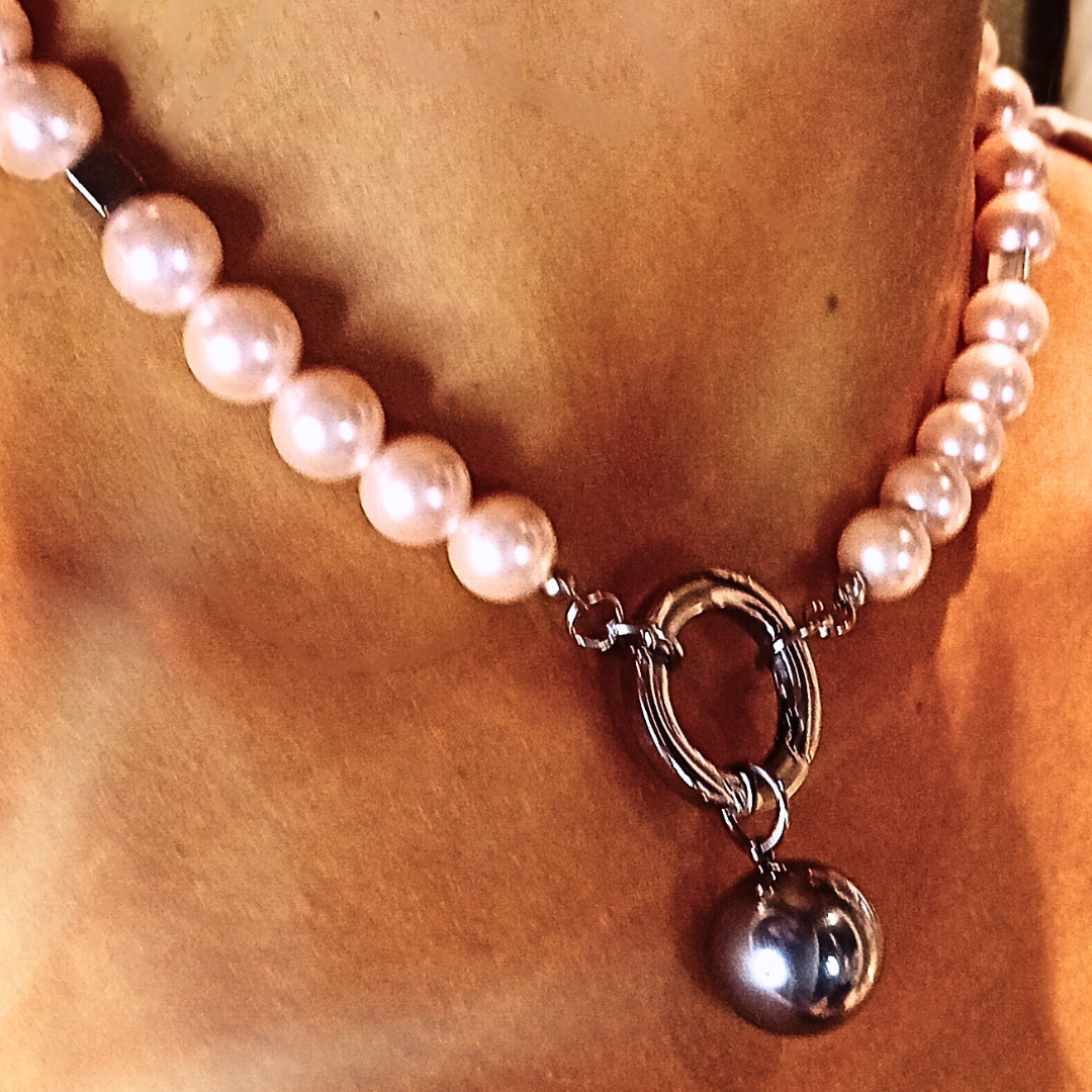 Modernt halsband i rostfritt stål med shell pearls och mörk droppe, buren nära halsen