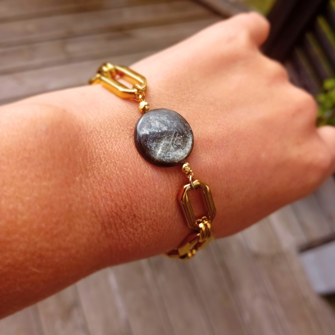 Armbandet Raven med golden mica-coin och grov guldpläterad länkkedja, buret på handleden.