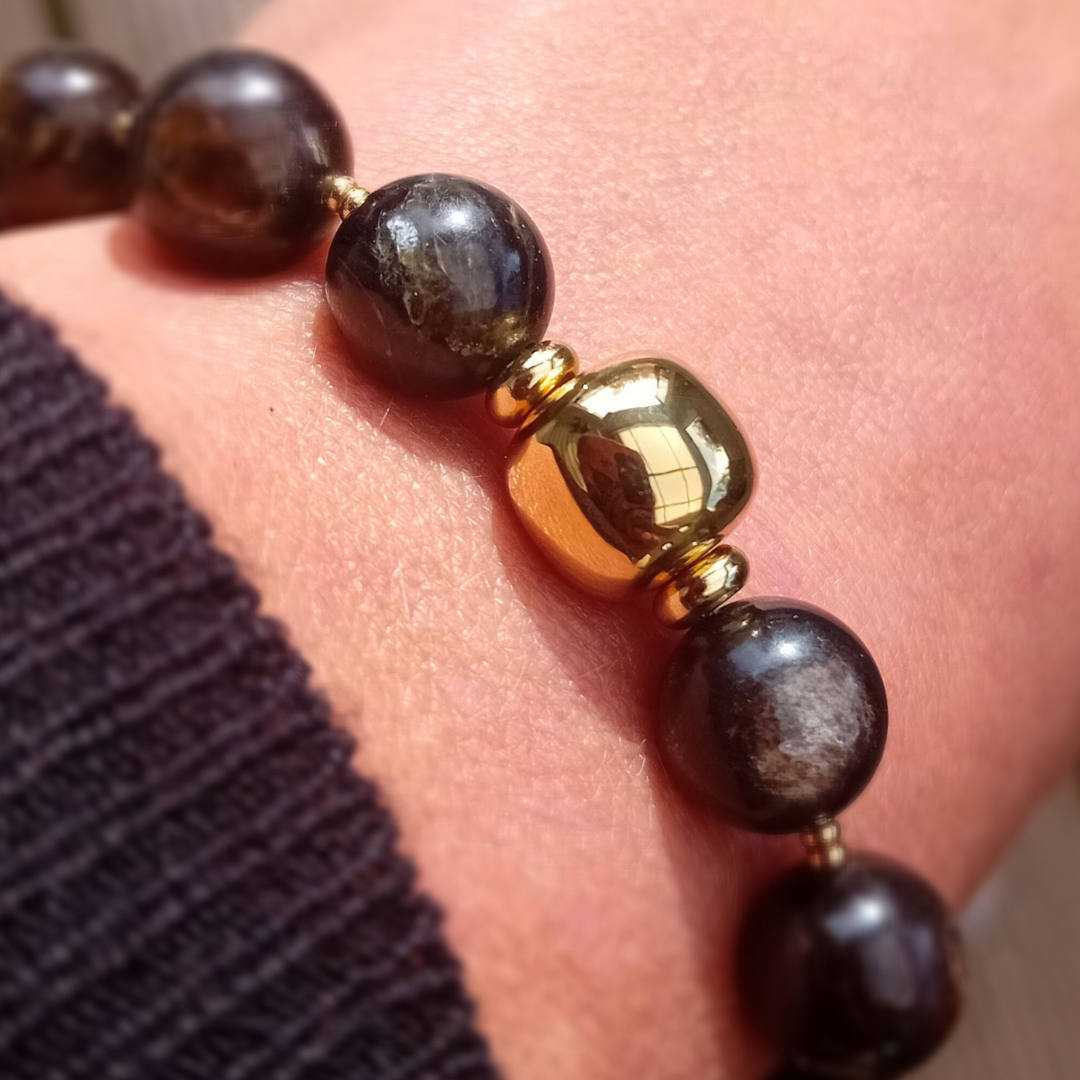 UMBRA-armband på handleden med mörka, runda pärlor i golden mica (12 mm) och en polerad guldpläterad pärla i rostfritt stål