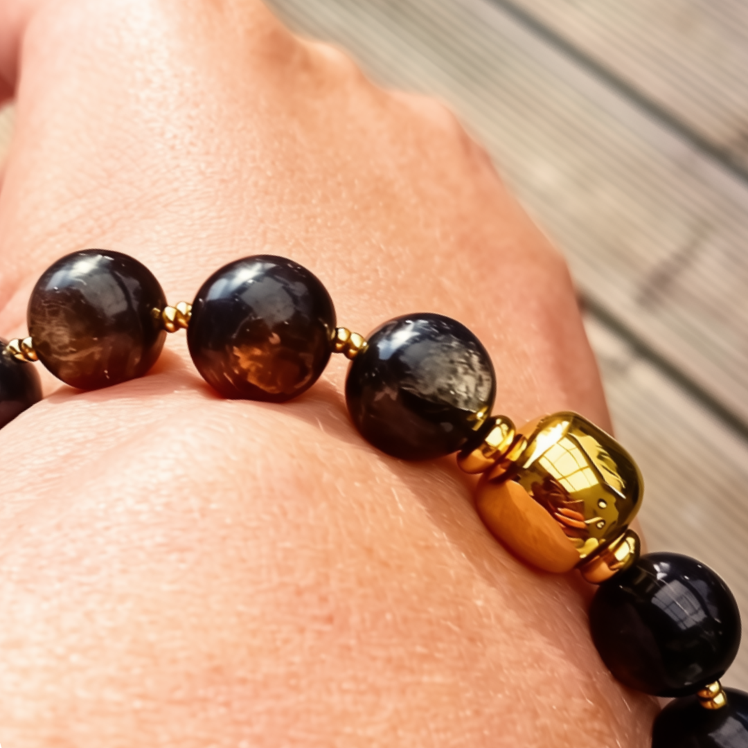 Närbild på UMBRA-armband med golden mica-pärlor och en polerad guldpläterad pärla mellan guldfärgade distanser